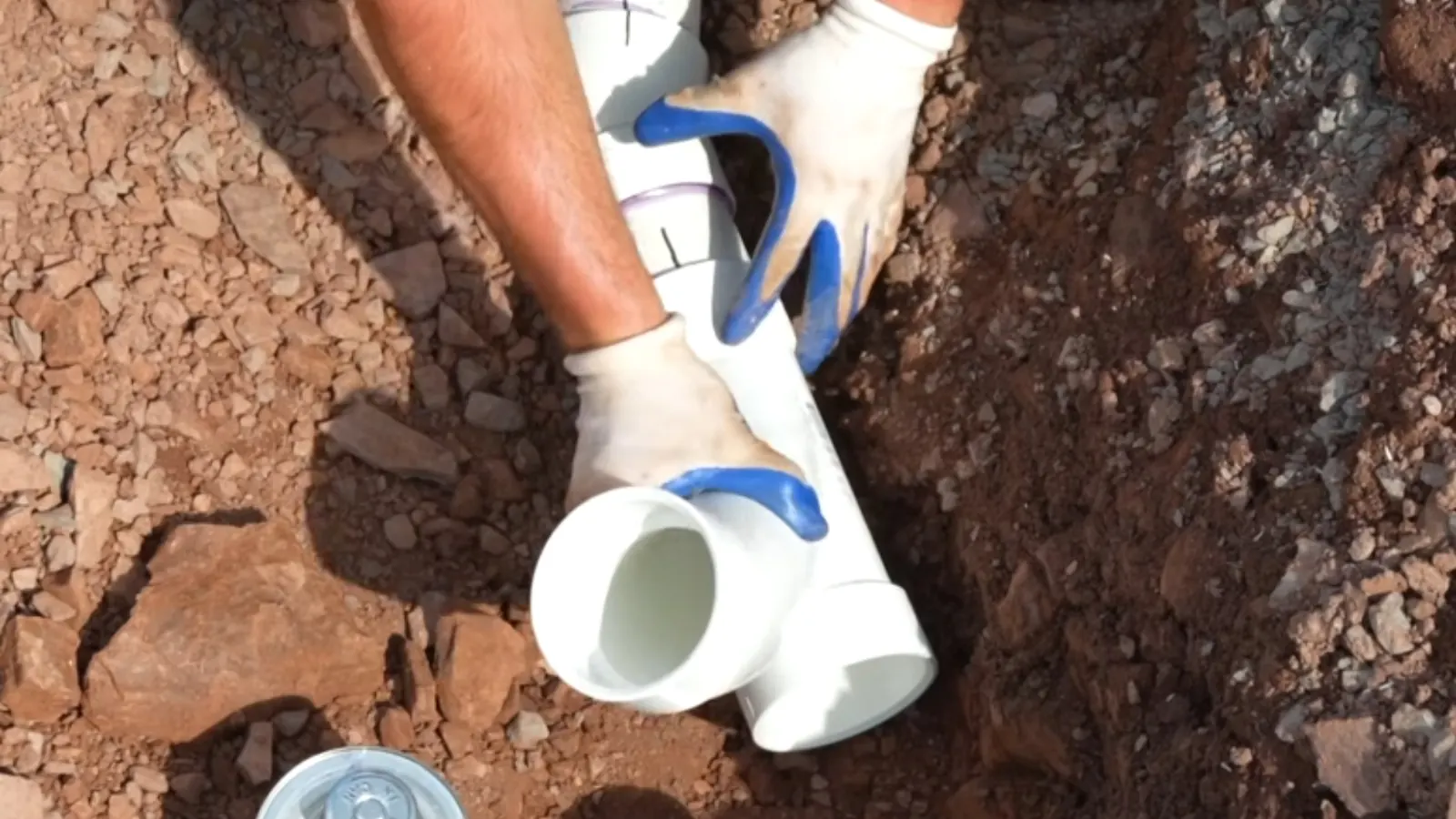 Worker fitting a new PVC section onto a sewer pipe in an open trench