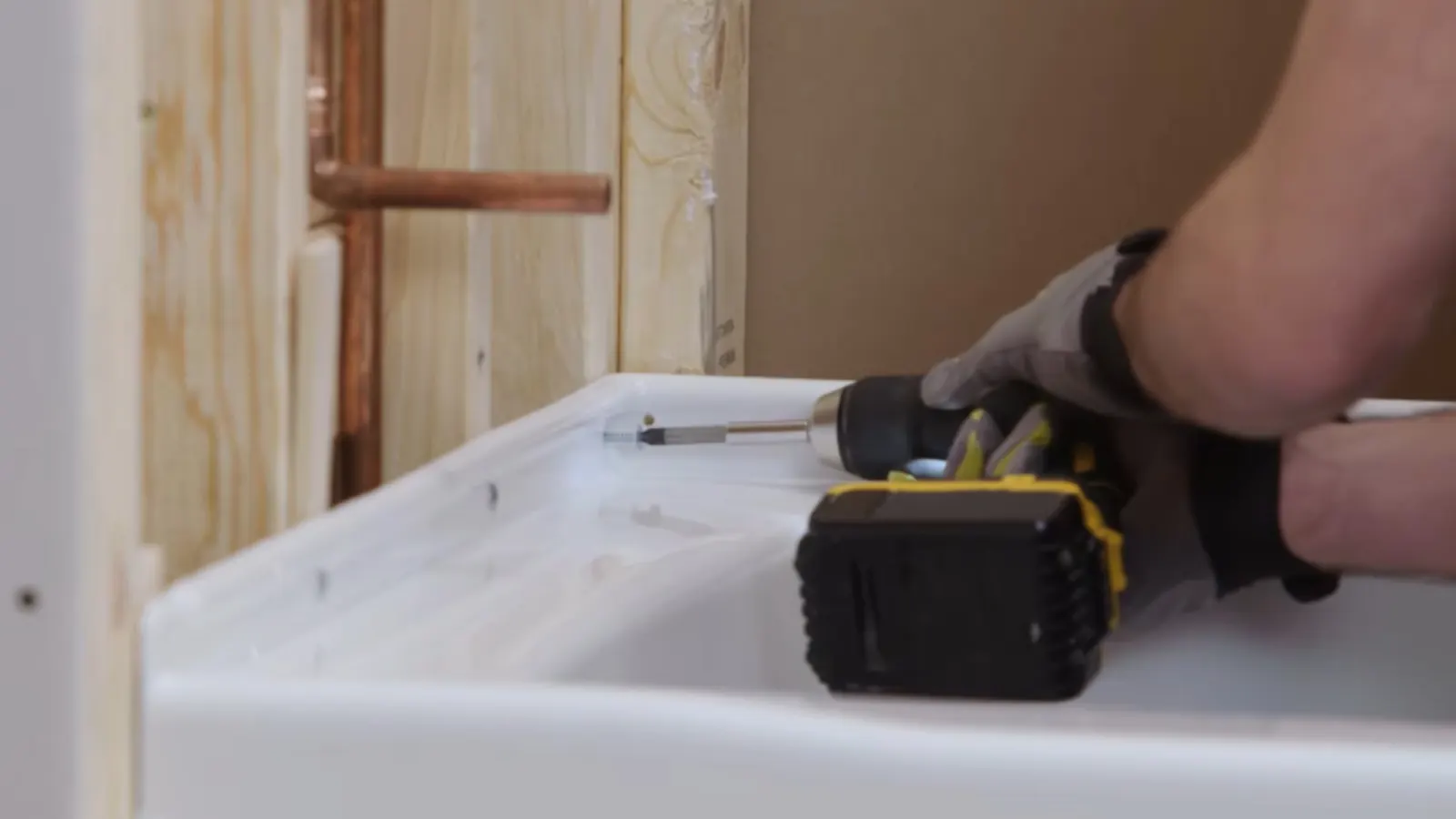 Installer fastening a new bathtub during a bathroom remodel