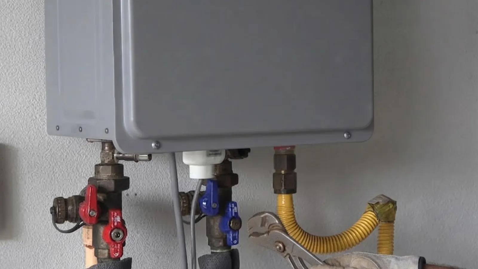 Wall-mounted tankless water heater with isolation valves and a yellow gas connector