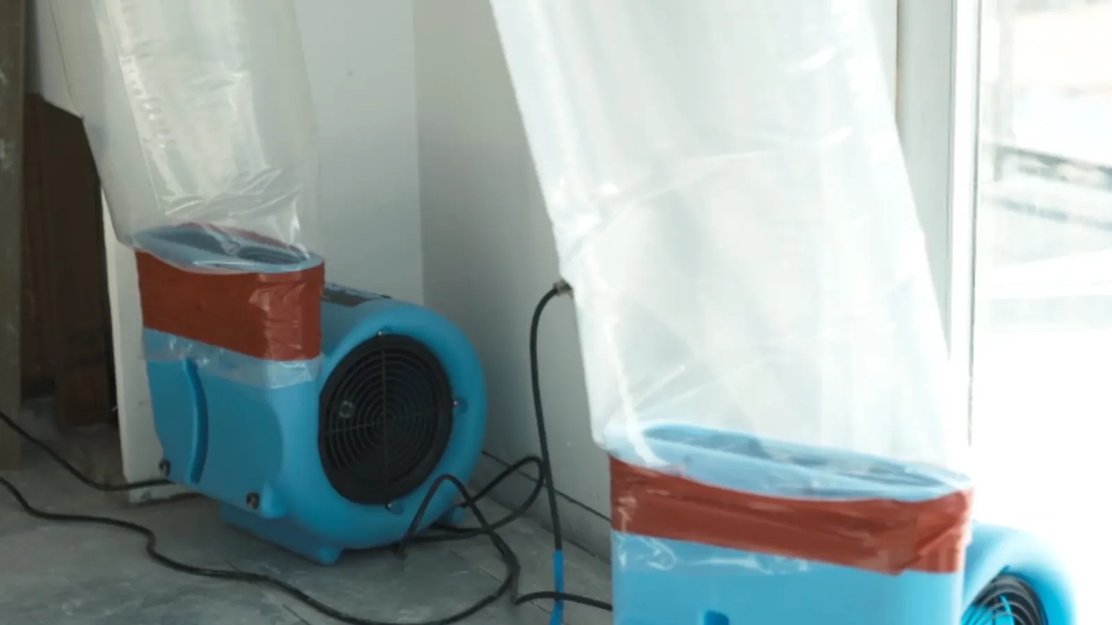 Air movers and drying ducts set up to dry a water-damaged room