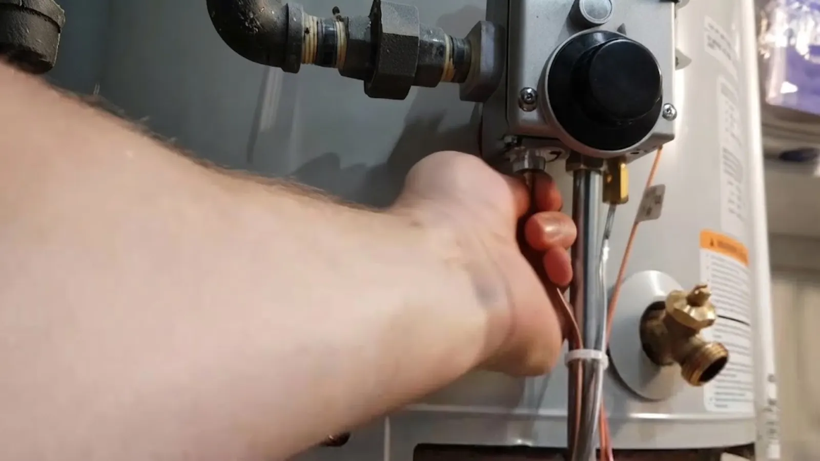 Plumber adjusting the gas control valve on a tank water heater