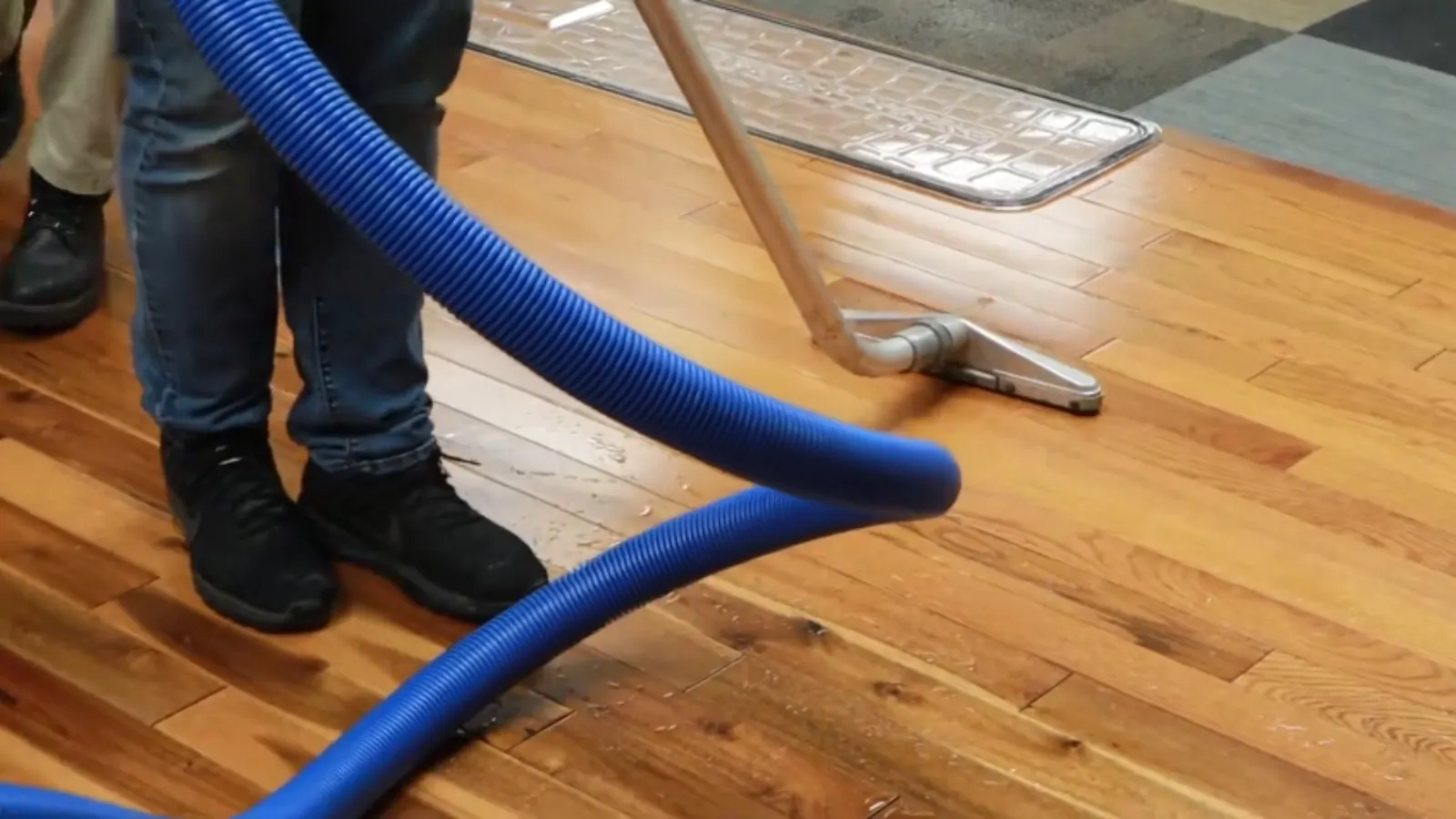 Technician extracting water from a hardwood floor with a vacuum wand