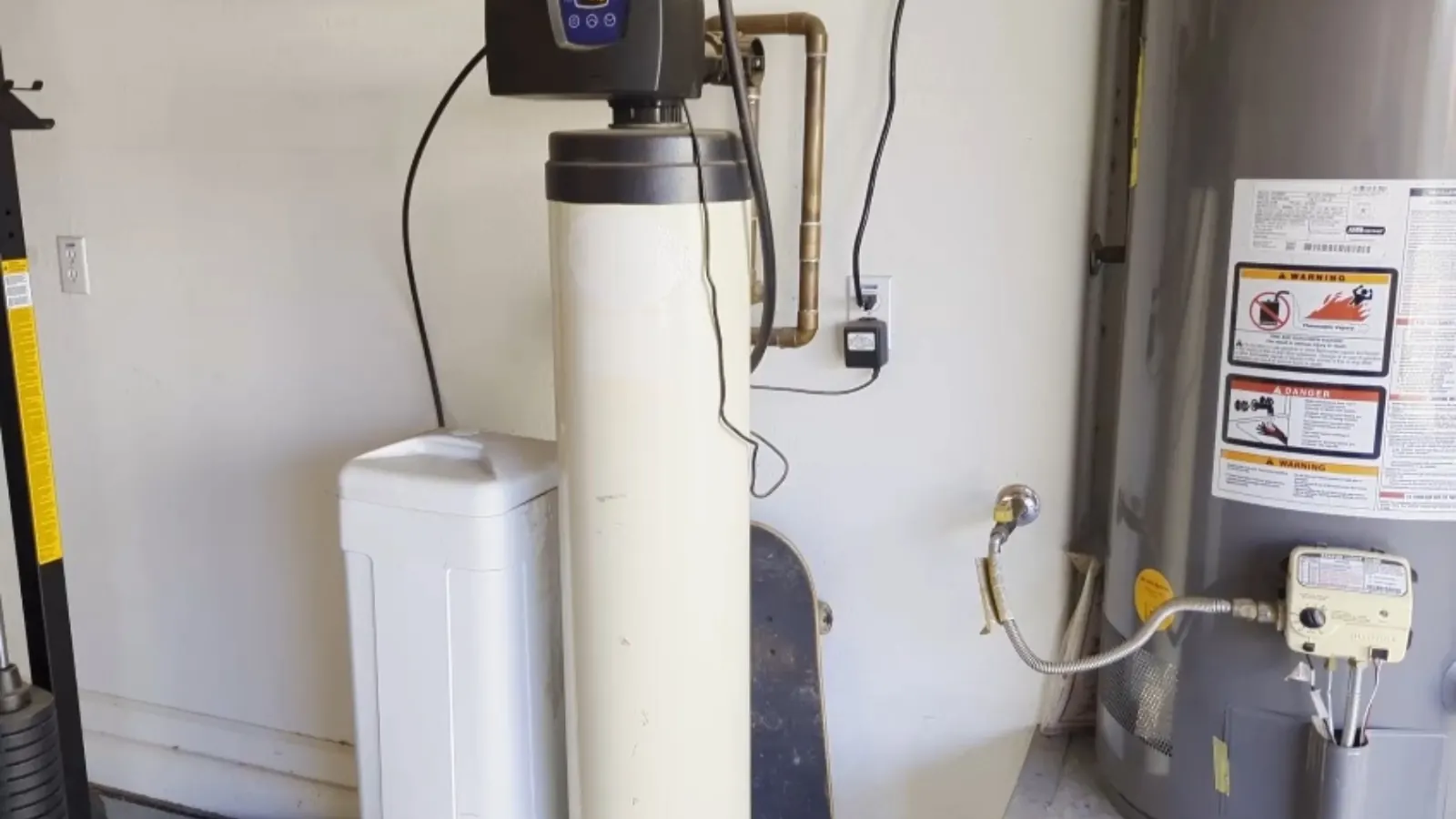 Water softener and brine tank installed beside a water heater in a garage